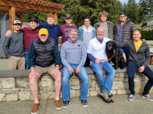 Eleven fraternity brothers of various ages and one dog together